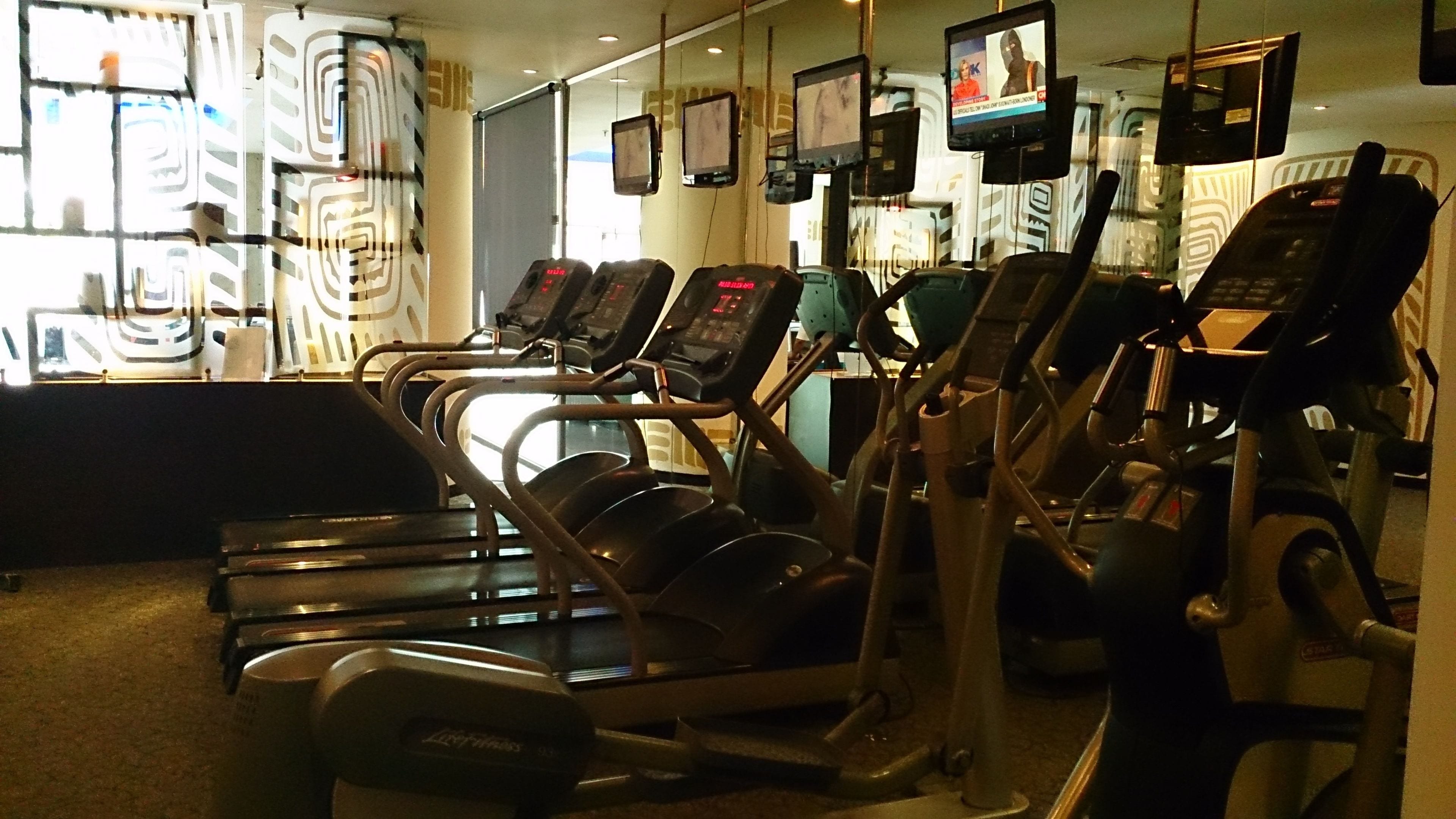 Un gimnasio con cintas de correr y equipo de ejercicio.