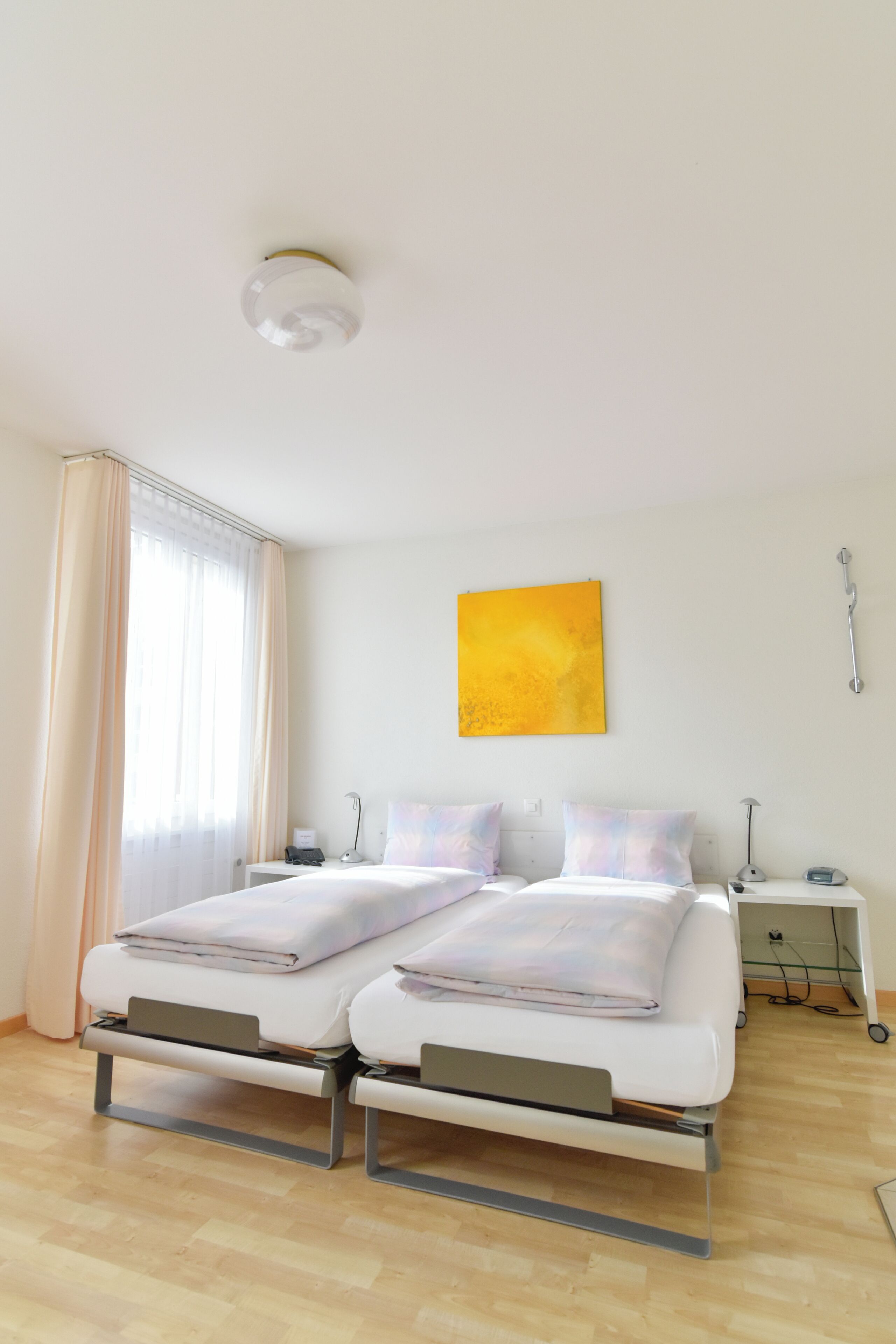 Un lit double avec une tête de lit, une table de chevet, une lampe et une œuvre d’art accrochée au mur.