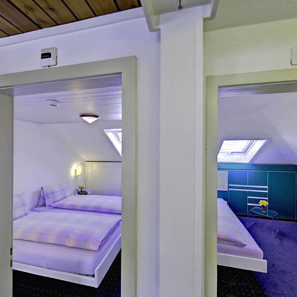 A modern hotel room with a bed, a desk, and a skylight.