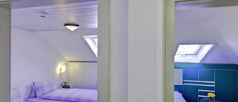 A modern hotel room with a bed, a desk, and a skylight.