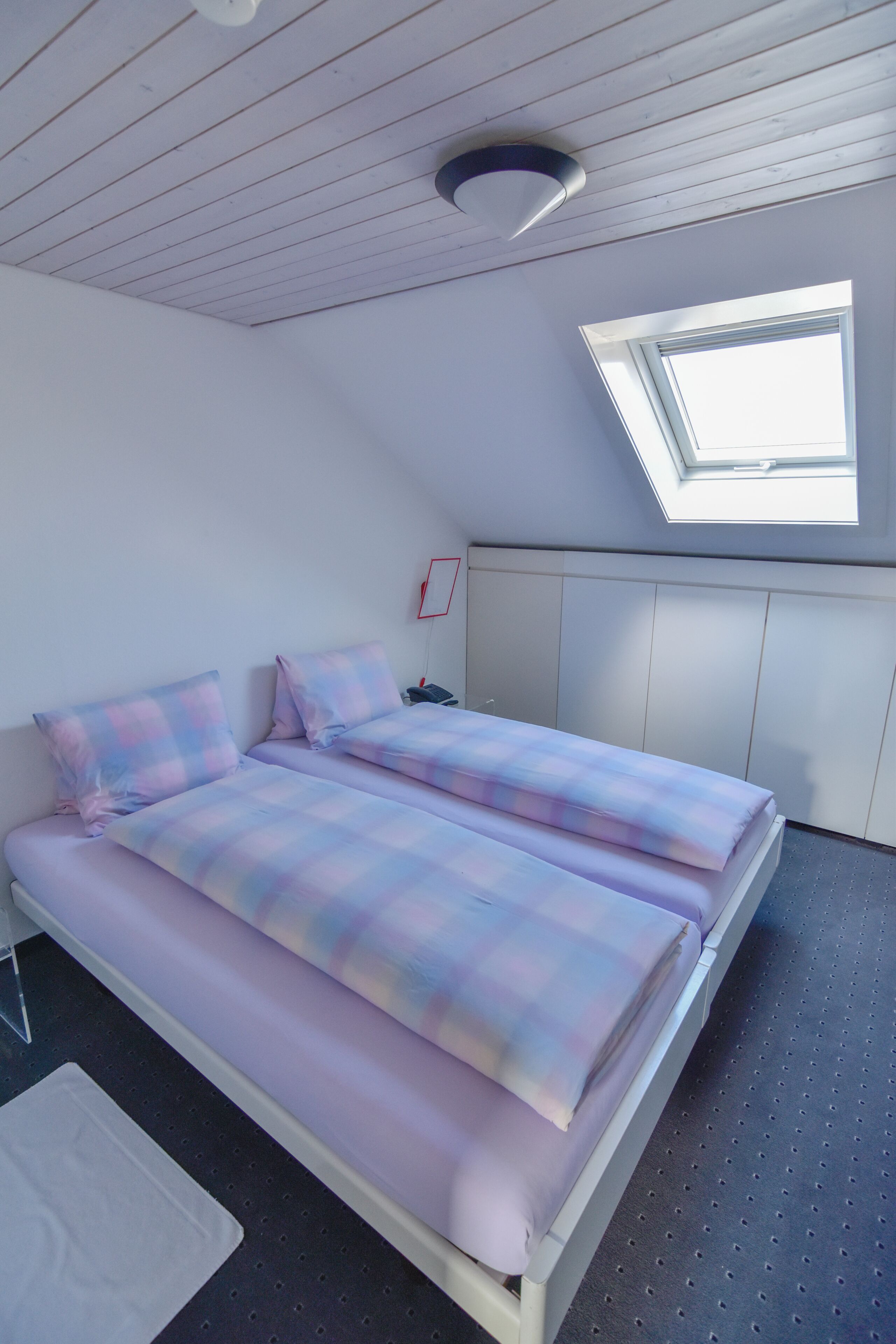 Een slaapkamer met twee bedden, dakraam en een wit plafond.