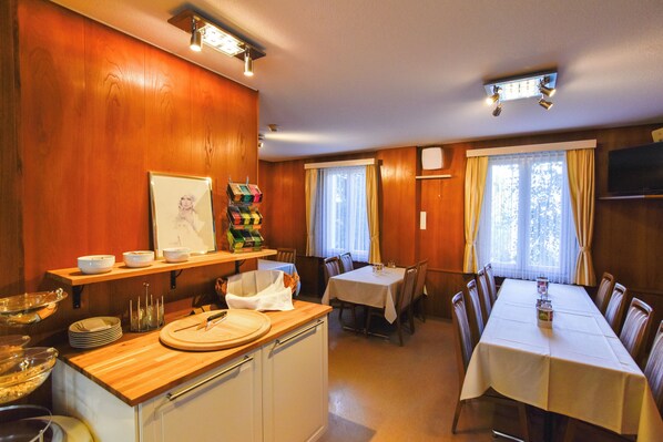 A dining area with a wooden interior, a buffet setup, and a television mounted on the wall.