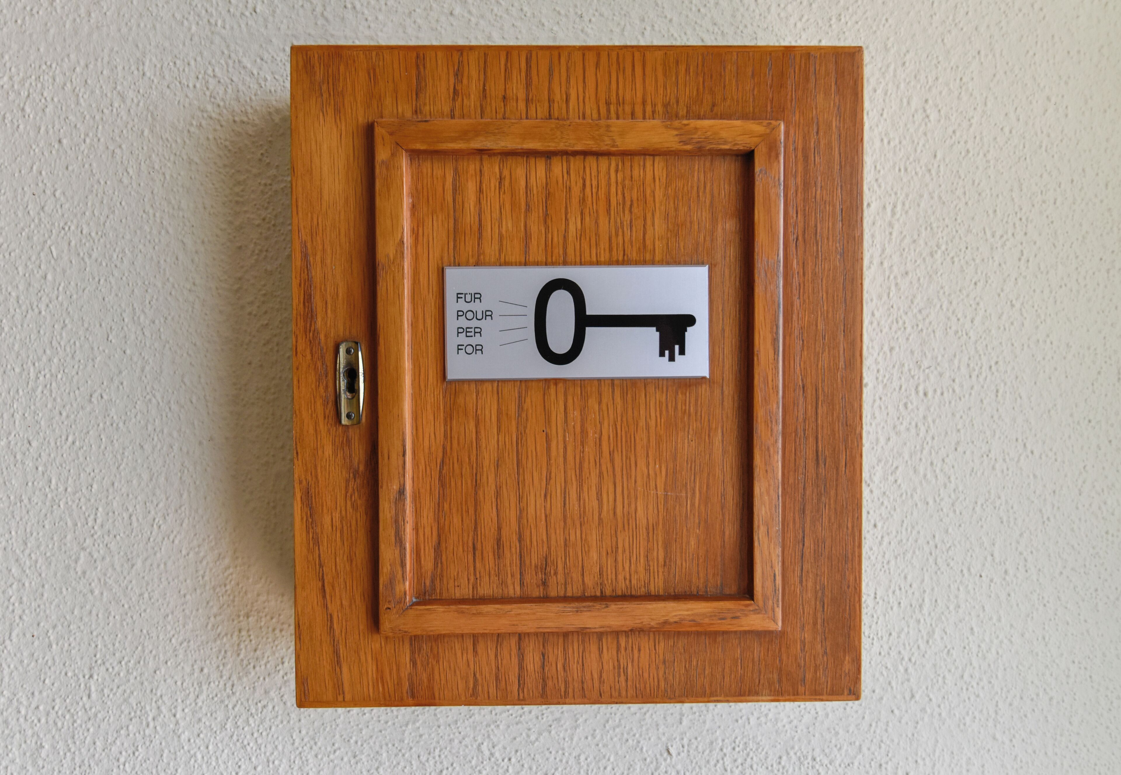 Un armario de madera con un letrero con forma de llave en la puerta.