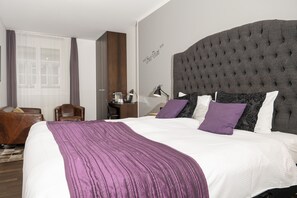 A hotel room with a large bed, a headboard, a desk with a lamp, a chair, and a window with curtains. - Boutique Hotel Weisses Kreuz - Adult only Hotel (Lucerne)