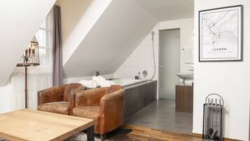 Ein modernes Wohnzimmer mit einem braunen Ledersofa, einem Holztisch und einem großen Fenster mit Vorhängen.