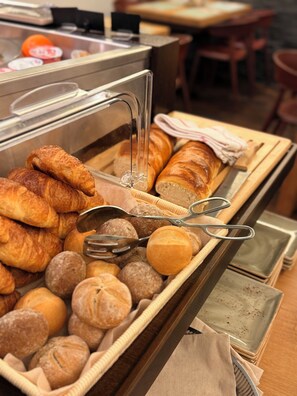 A buffet with various baked goods including croissants, bread rolls, and baguettes. - Boutique Hotel Weisses Kreuz - Adult only Hotel (Lucerne)