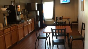 Une cuisine spacieuse avec des meubles en bois, un coin repas comprenant une table et des chaises, un réfrigérateur et un téléviseur à écran plat fixé au mur.