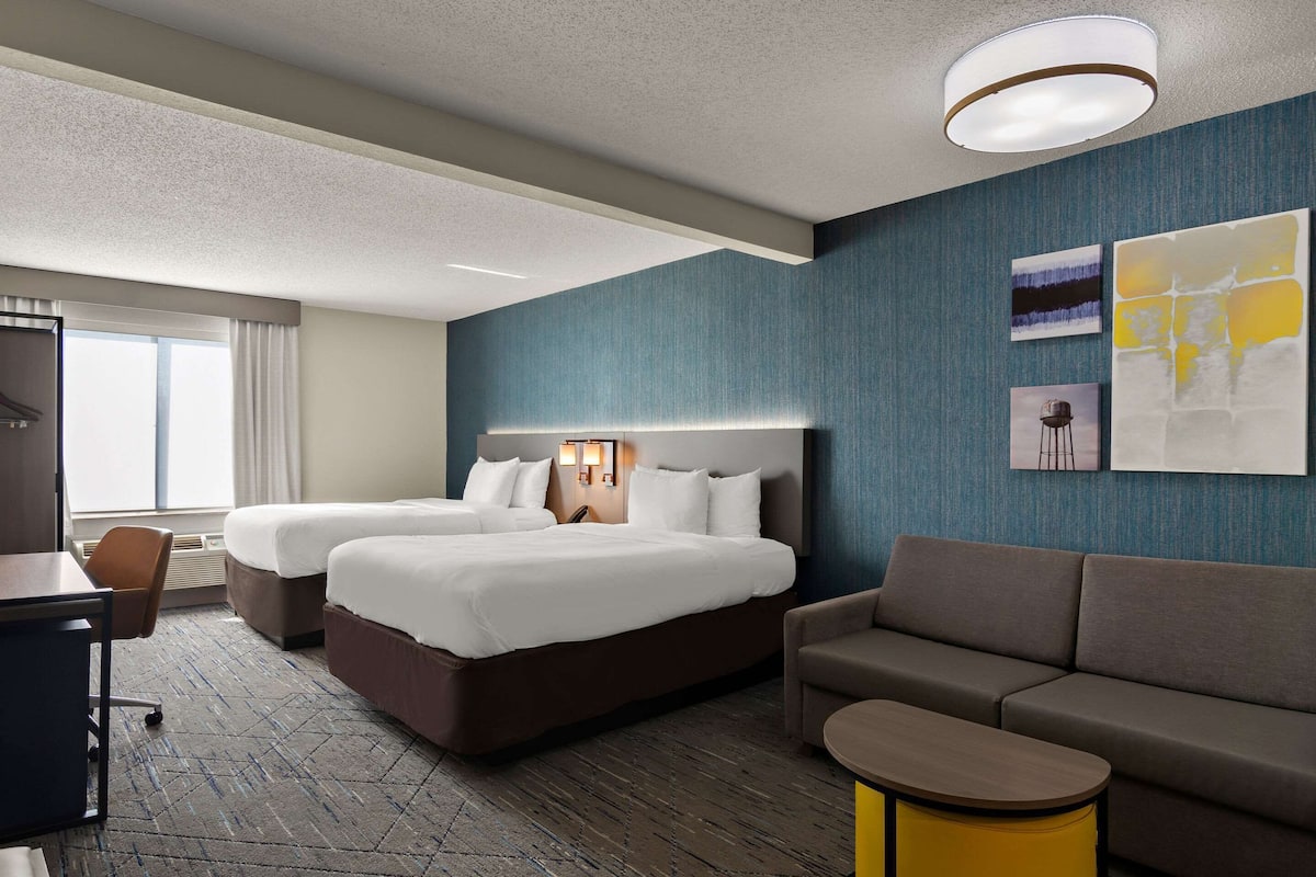 Ett hotellrum med två sängar, en soffa, ett skrivbord och en stol.