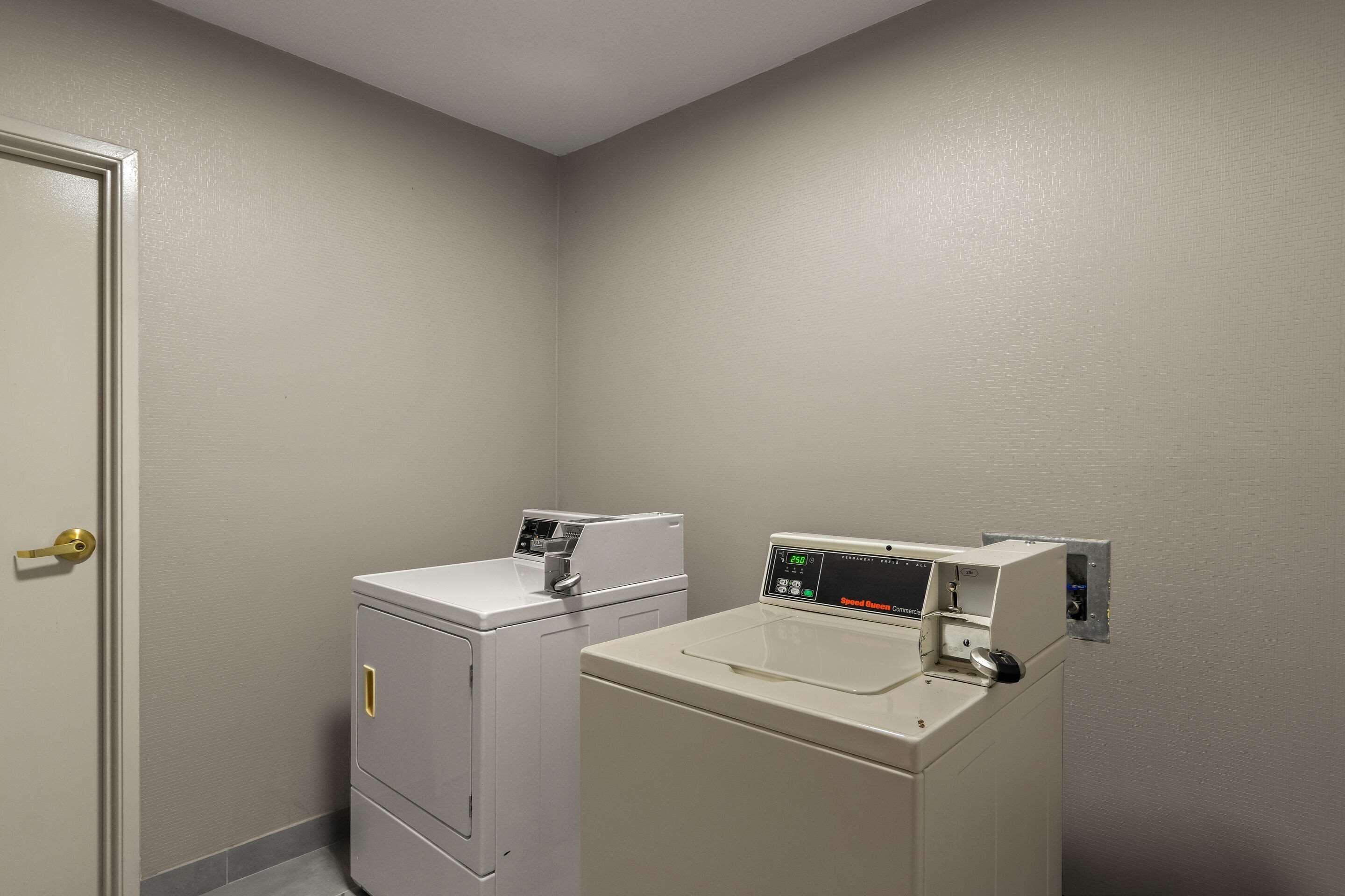 A laundry room with two washing machines and a dryer.