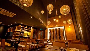 A restaurant interior with wooden furniture, hanging spherical chandeliers, and a wine rack.