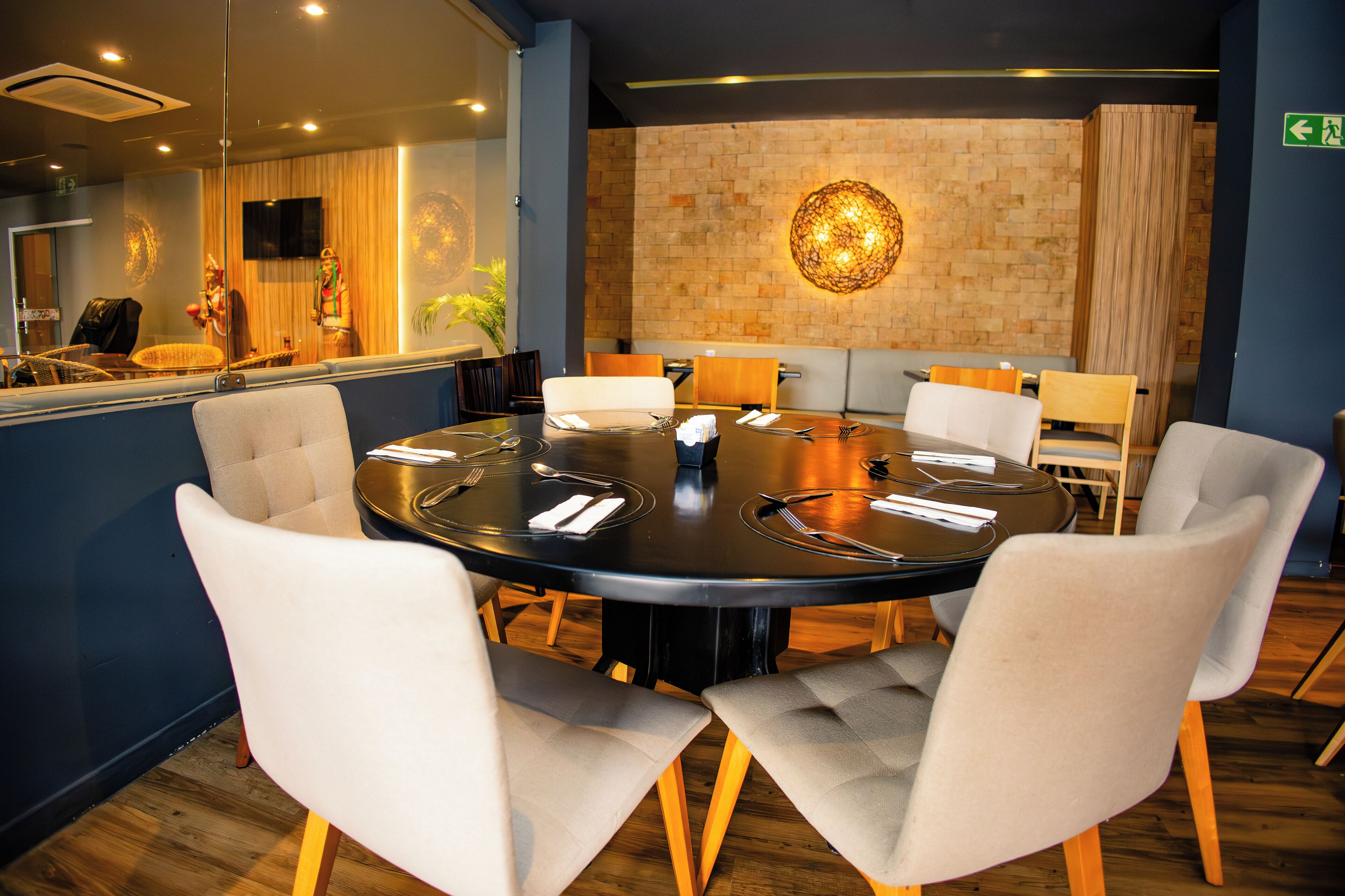 A conference room with a round table, white chairs, and a brick wall with a decorative light fixture.