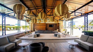 A spacious lounge area with a large sofa set, multiple seating options, and hanging wicker lamps.