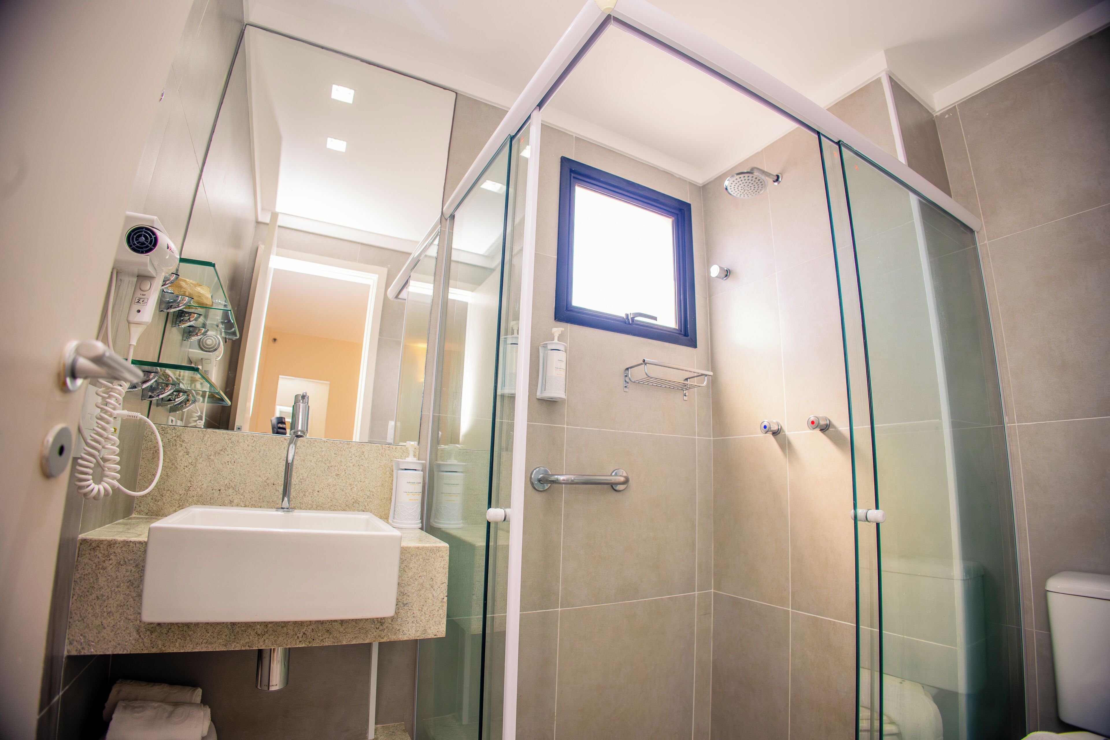 Une salle de bain moderne avec une douche à parois de verre, un lavabo avec un miroir et un porte-serviettes.