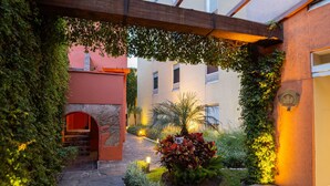 Une cour avec un chemin en pierre, une arche rouge et un petit jardin agrémenté de plantes et d’un pot décoratif.