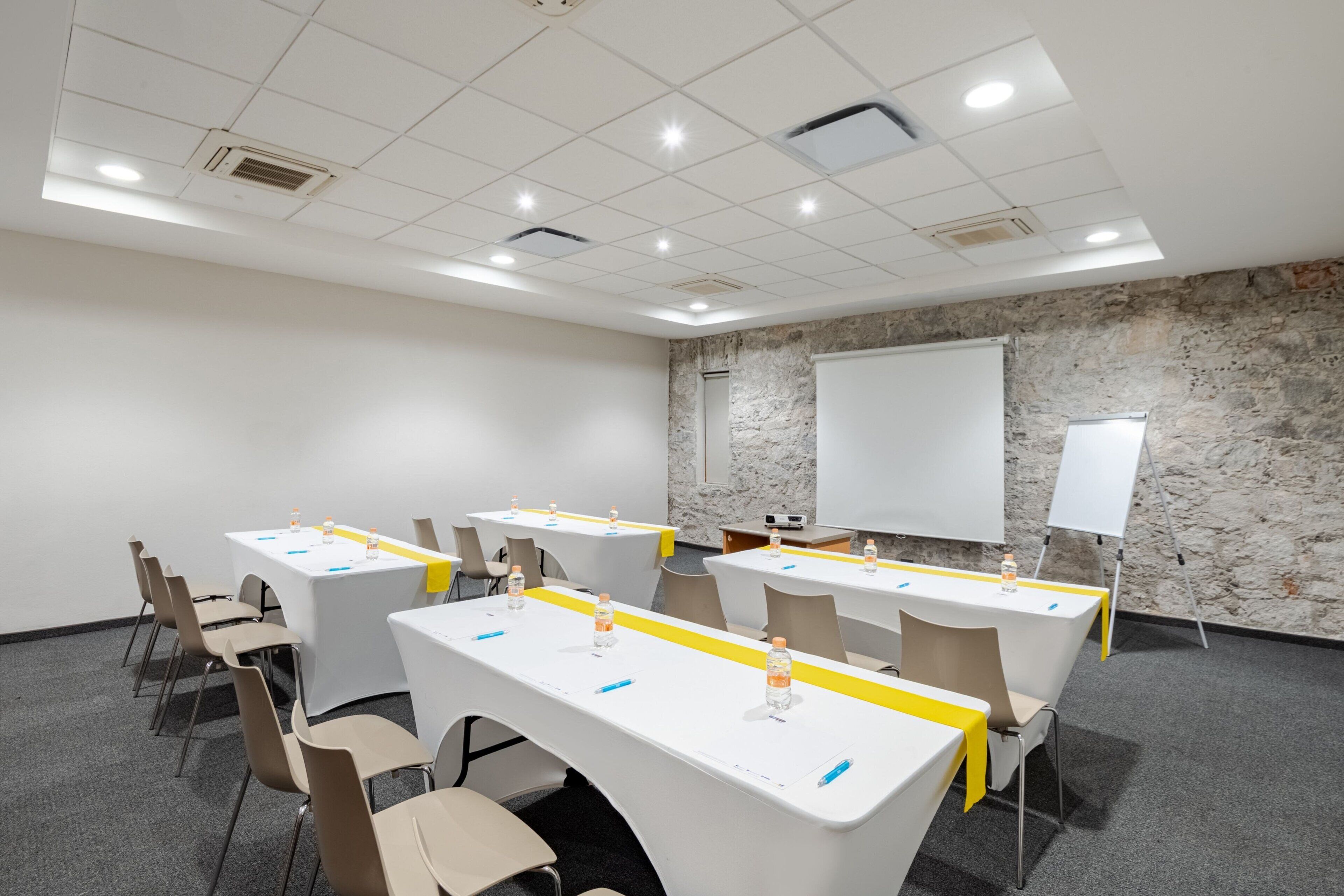A conference room with white tables, chairs, and a whiteboard.