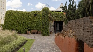 Une cour avec un chemin en pierre, un mur en briques et un jardin de cactus.