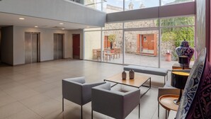 Un hall d’entrée spacieux, doté d’un haut plafond, de grandes fenêtres et offrant une vue sur la terrasse extérieure.