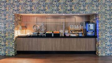 Zona de buffet amb un mostrador, diferents plats, una màquina de cafè i una vitrina de vidre.