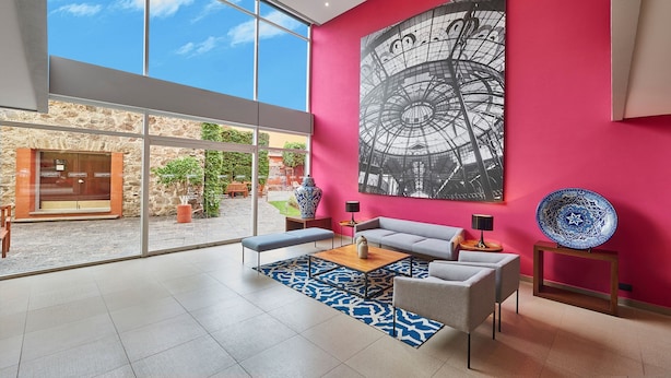 Un hall d’entrée moderne avec une grande baie vitrée, un mur rouge et une grande œuvre d’art en noir et blanc.
