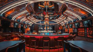 A bar area with a central bar counter, multiple seating arrangements, and a decorative ceiling.