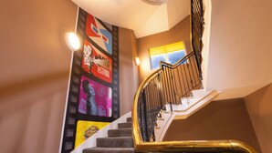 A staircase with a handrail, a wall with movie festival posters, and a window with daylight. - The Camden Hotel (Dublin)