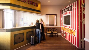 A reception area with a 'Box Office' sign, a 'Fresh Popcorn' sign, and a seating area with chairs. - The Camden Hotel (Dublin)