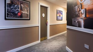 A hallway with framed movie posters, a door with a number sign, and a carpeted floor. - The Camden Hotel (Dublin)