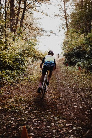 A cyclist on a dirt path surrounded by trees. - Hotel Papendal (Arnhem)