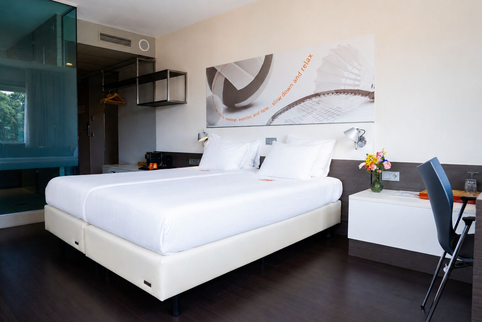 Een moderne hotelkamer met een groot bed, nachtkastjes, een bureau en een stoel.