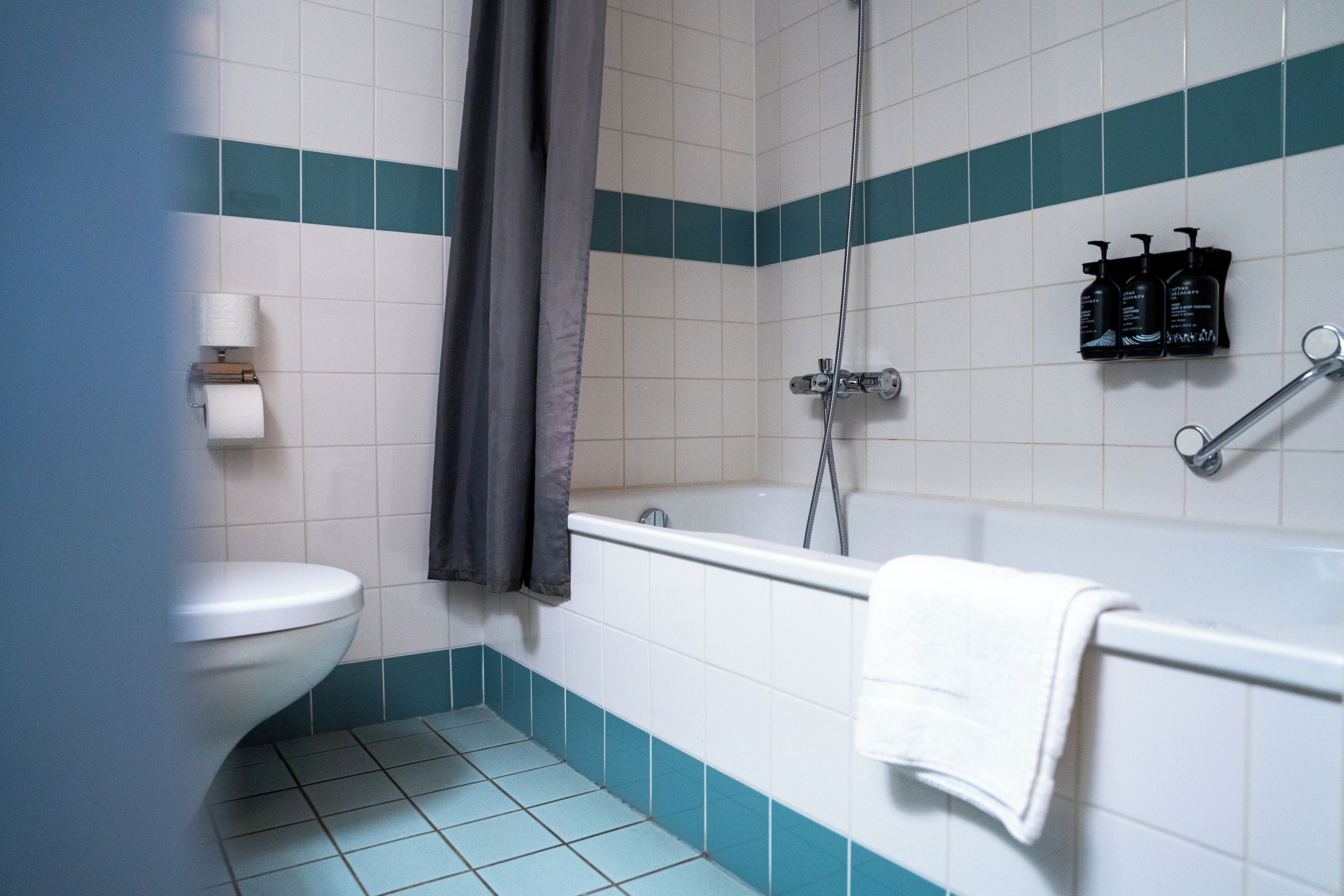 A bathroom with a toilet, a bathtub, and a shower. There are toiletries on the wall.