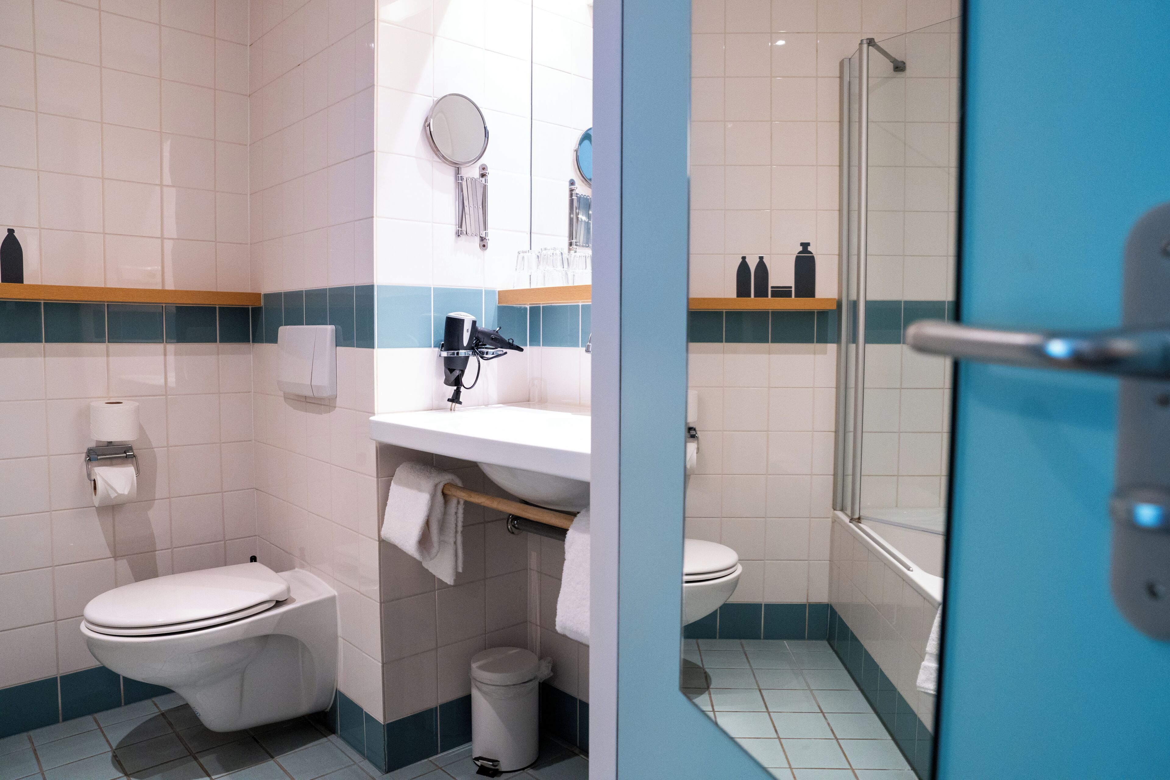 A bathroom with a toilet, sink, and mirror.