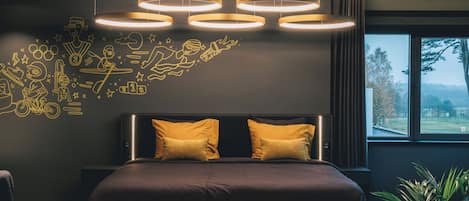 Un dormitorio moderno con una cama grande, cabecera con dos almohadas y una pared decorada con dibujos estilo garabato.