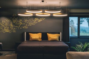 A modern bedroom with a large bed, a headboard with two pillows, and a wall with doodle-style drawings. - Hotel Papendal (Arnhem)