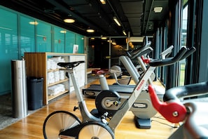 Un gimnasio con bicicletas estáticas, cinta de correr y un armario con taquillas.