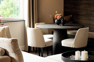 Un comedor moderno con una mesa redonda, dos sillas, un florero con flores y un candelabro con velas.