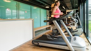 A gym with treadmills, exercise equipment, and a teal-colored wall with lockers. - Hotel Papendal (Arnhem)