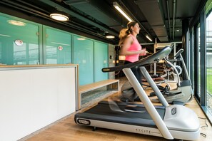 A gym with treadmills, exercise equipment, and a teal-colored wall with lockers. - Hotel Papendal (Arnhem)