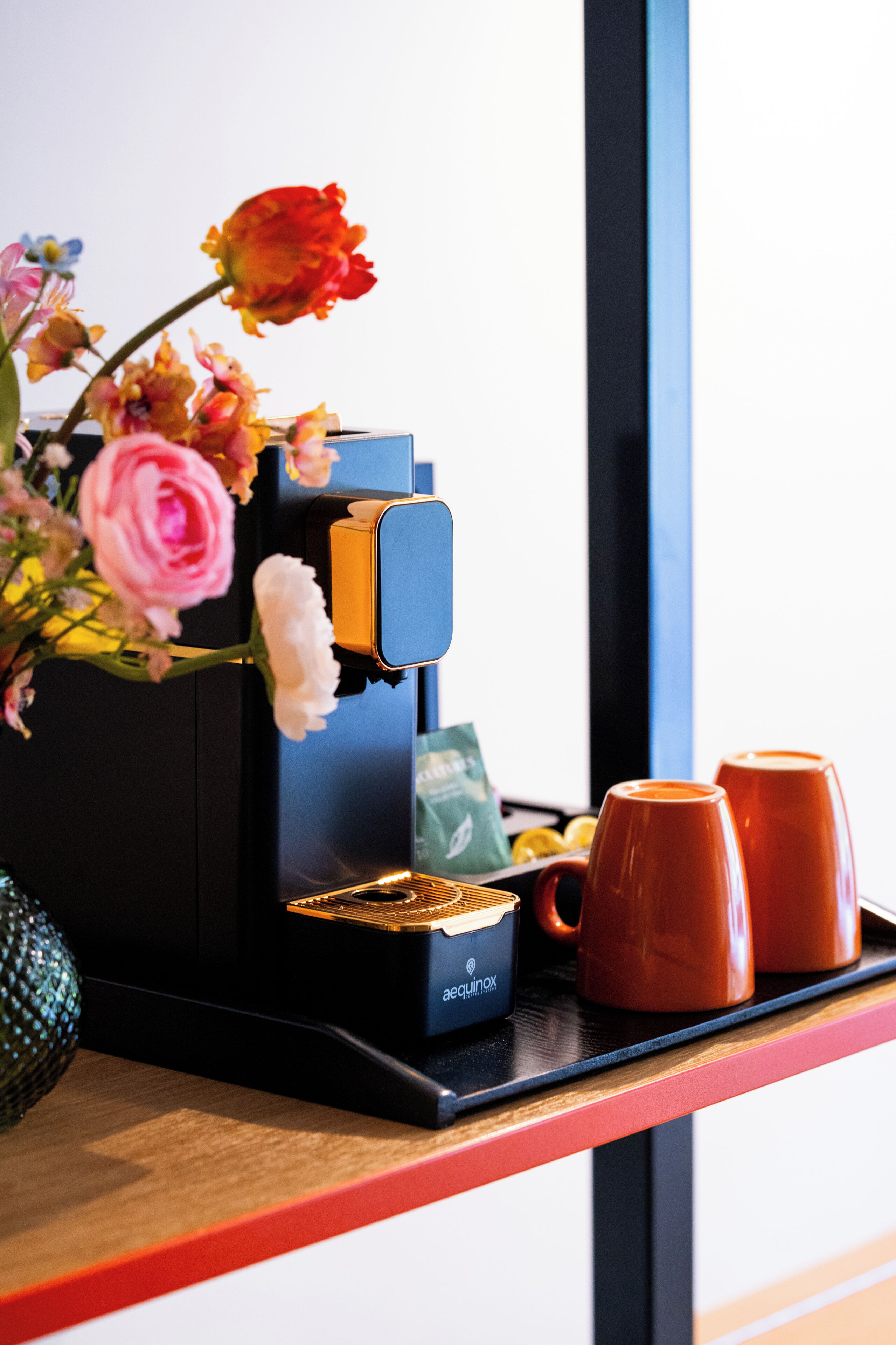 A coffee machine with a water reservoir, a coffee pod holder, and two cups on a tray.