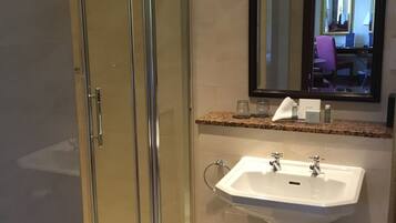 A modern bathroom with a glass shower enclosure, a white sink with a mirror above it, and a granite countertop.