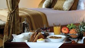 A neatly arranged breakfast tray with various food items and a glass of orange juice on a bed. - Macdonald Drumossie Hotel (Inverness)