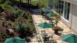 A patio with outdoor seating and a garden area. - Macdonald Drumossie Hotel (Inverness)