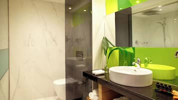 A modern bathroom with a marble floor, a white toilet, a black vanity with a white sink, and a green accent wall.