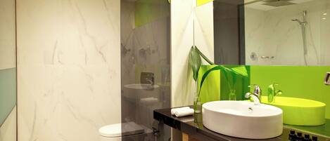 A modern bathroom with a marble floor, a white toilet, a black vanity with a white sink, and a green accent wall.