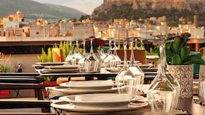 A table set for dining with a view of a historic building in the background. - Zeus Wyndham Grand Athens (Athens)