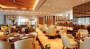 A spacious hotel lobby with multiple seating areas, a bar, and a reception desk.