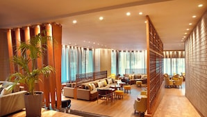 A spacious lobby with a sofa area, wooden partitions, and a potted plant. - Zeus Wyndham Grand Athens (Athens)
