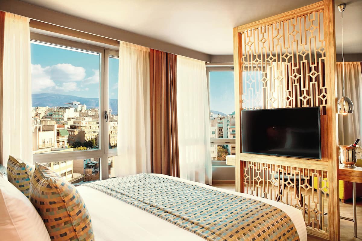 Una camera d'albergo con un letto grande, una televisione e vista sulla città.