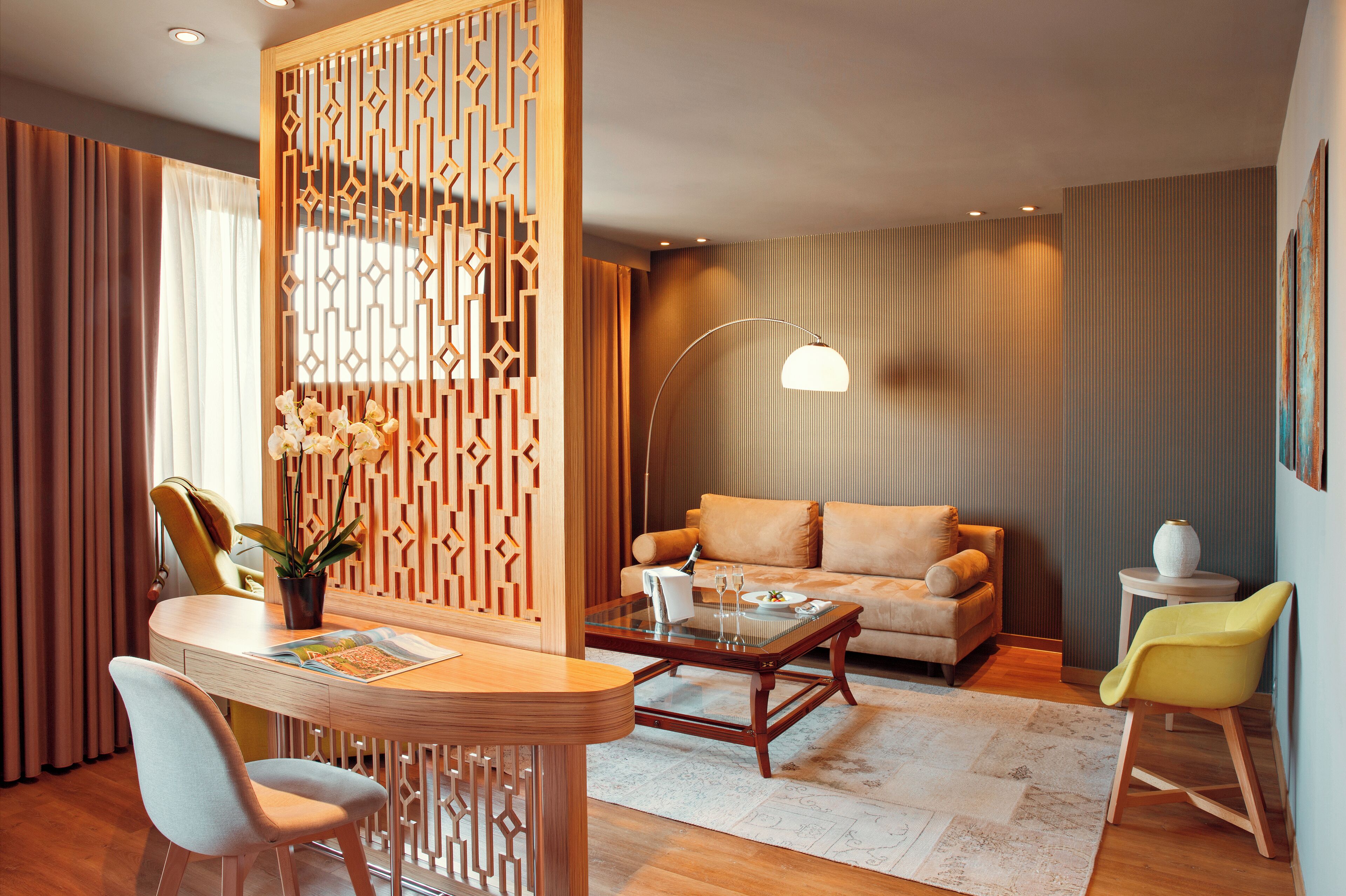 A modern living room with a round wooden coffee table, a sofa, and a dining area with a wooden table and chairs.