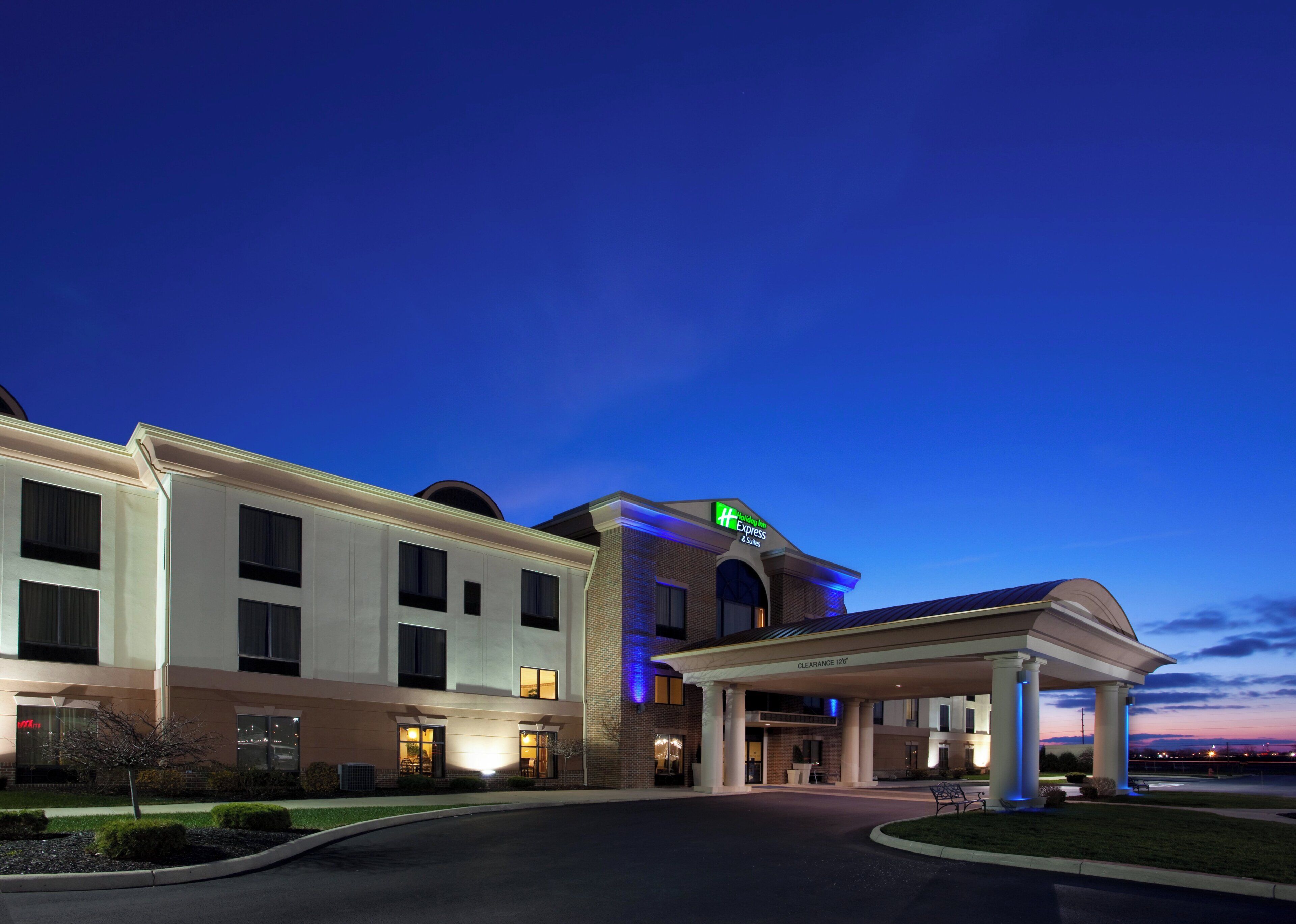 Un hotel con entrada despejada, zona de estacionamiento y fachada bien iluminada.