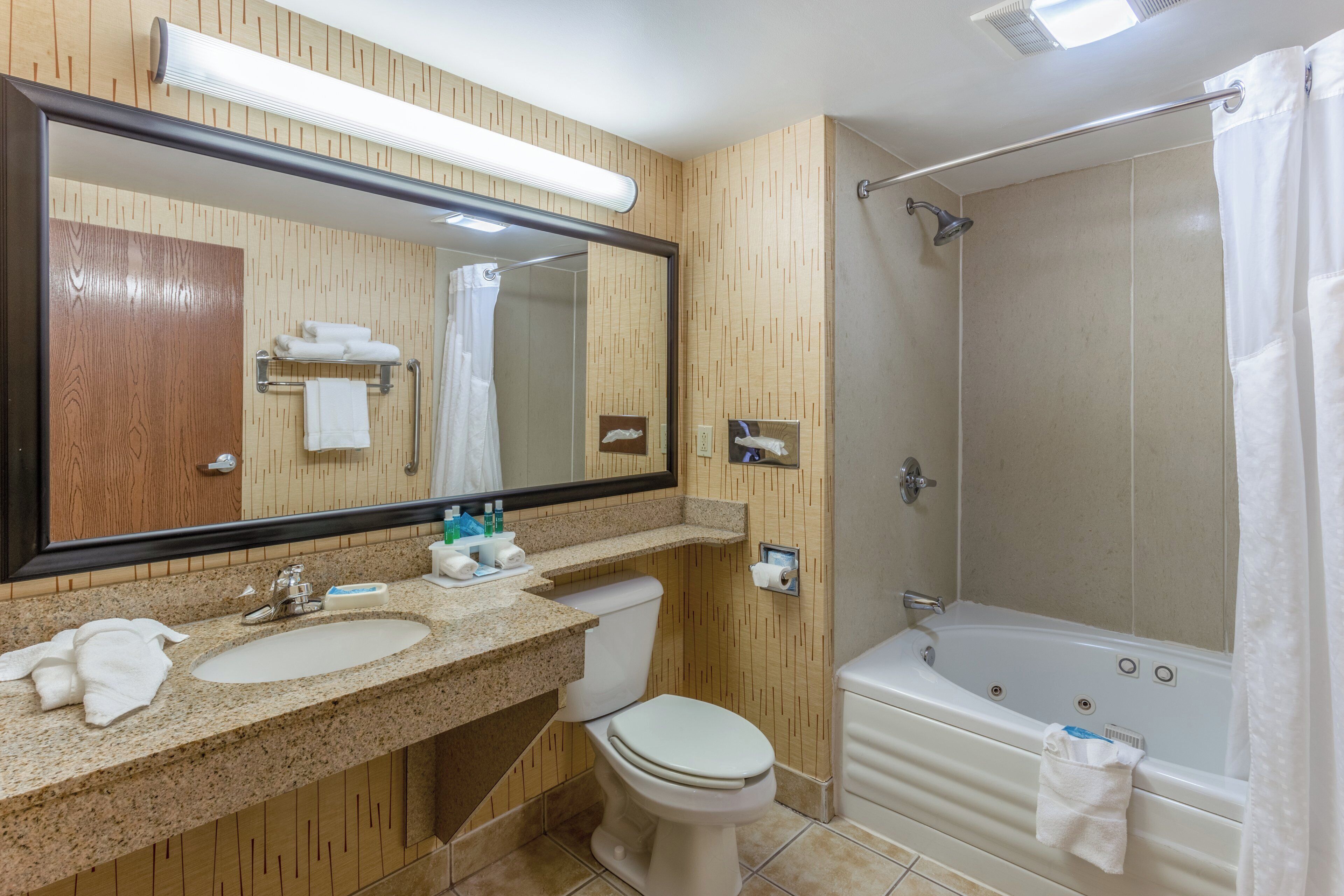 A bathroom with a wooden vanity, a toilet, a bathtub, and a shower.